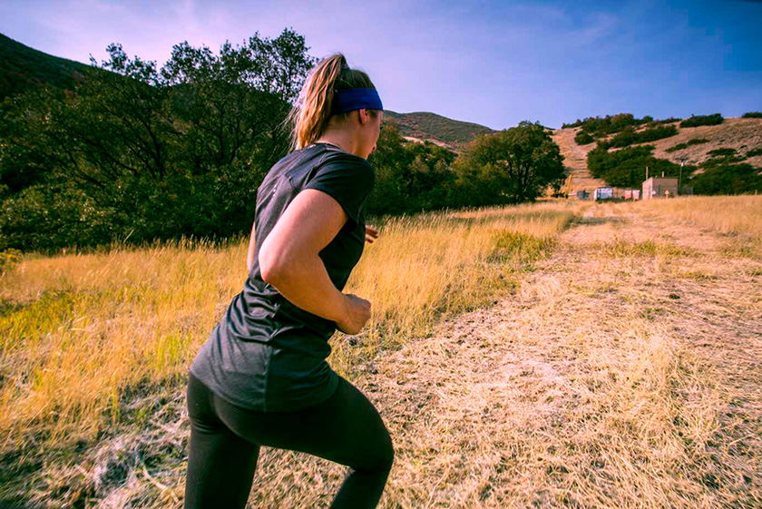 Девушка в спортивных леггинсах и футболке бежит по горной тропинке Женщина на пробежке на сельской дороге